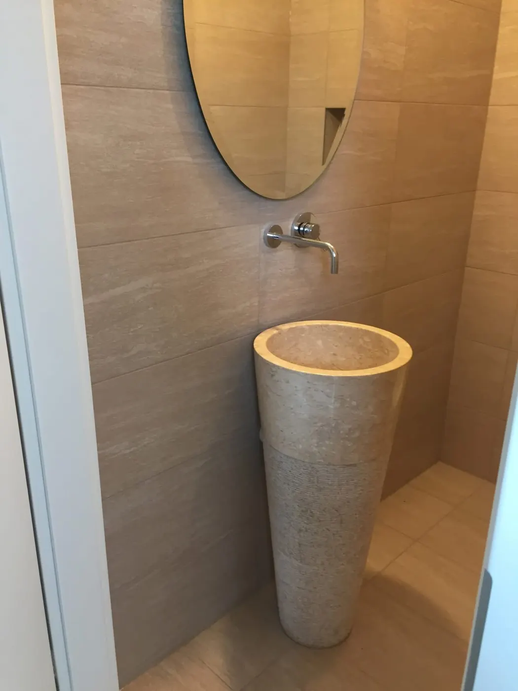 Toilettes en carrelage beige avec vasque colonne