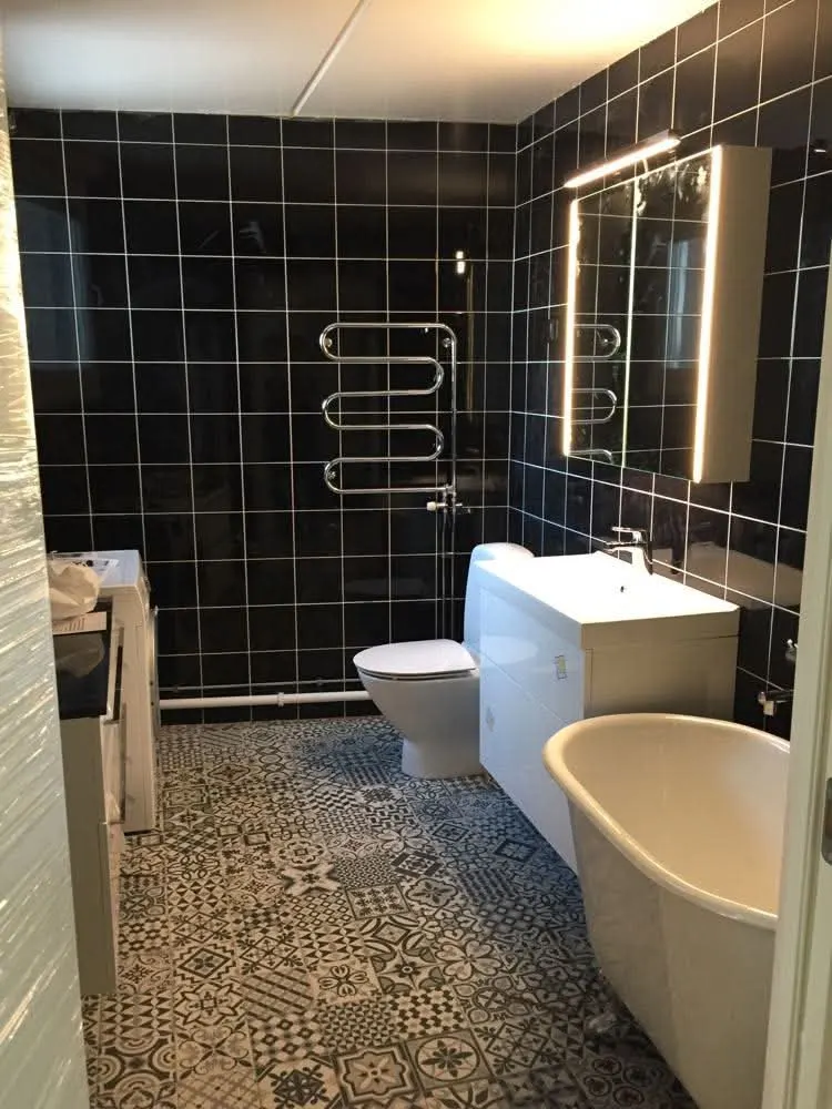 Salle de bain en carrelage noir avec baignoire et sol à motifs
