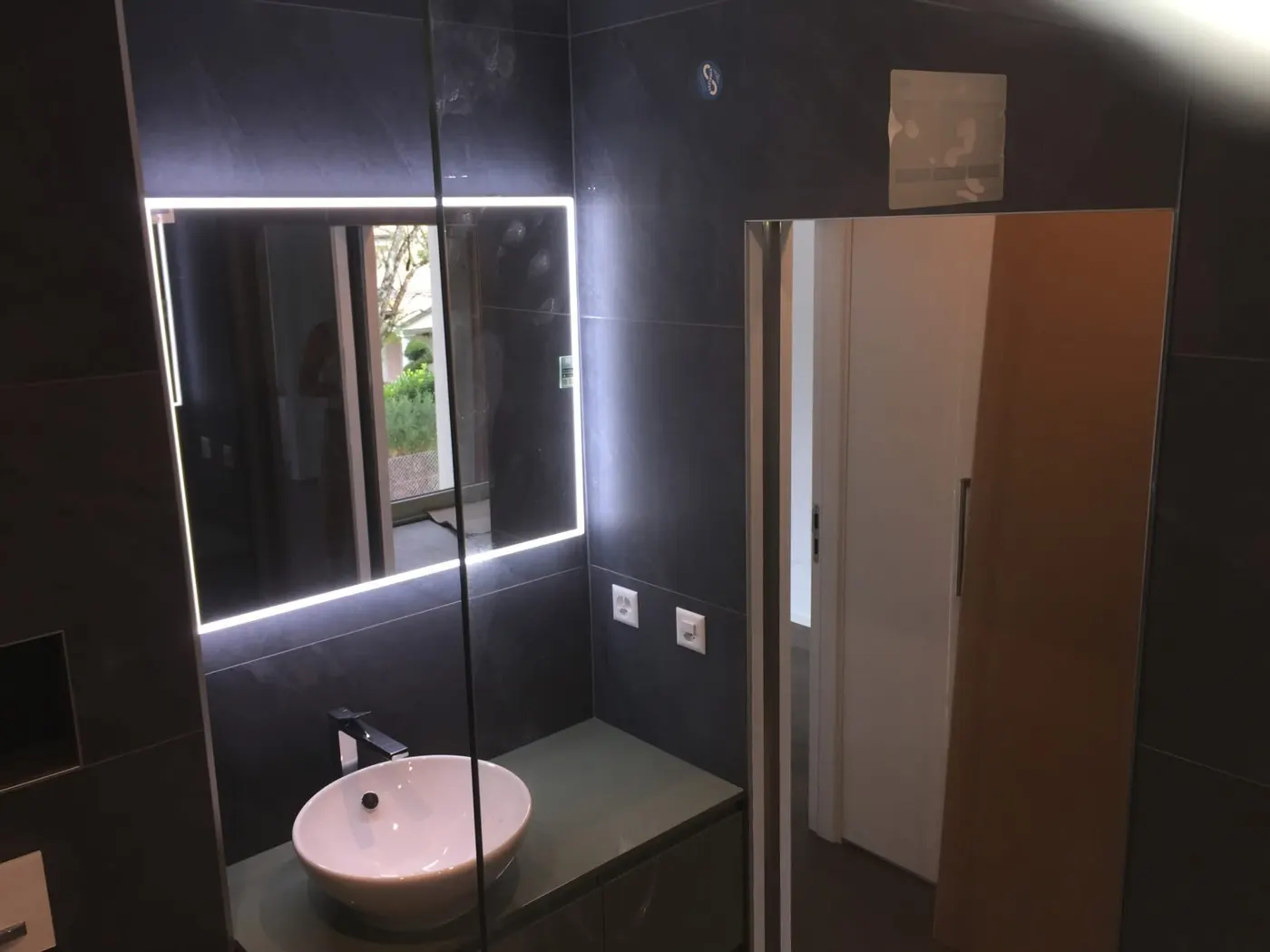 Salle de bain en carrelage anthracite avec miroir lumineux